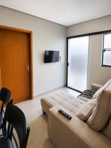 ein Wohnzimmer mit Sofa und Fernseher in der Unterkunft Flat AR Moderno com Ar Condicionado e Estacionamento in Rio Claro