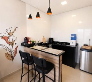 eine Küche mit einer Bar mit Stühlen und einer Theke in der Unterkunft Flat AR Moderno com Ar Condicionado e Estacionamento in Rio Claro