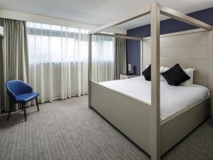 a bedroom with a canopy bed and a chair at Mercure Manchester Piccadilly Hotel in Manchester