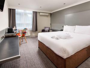 a hotel room with a large bed and a desk at Mercure Chester Abbots Well Hotel in Chester