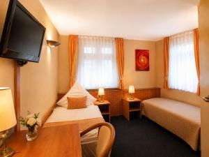 a hotel room with two beds and a flat screen tv at Hotel Altes Rathaus in Ostfildern