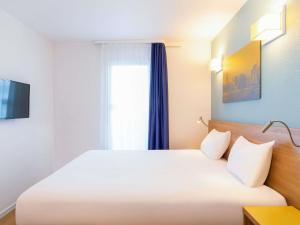 a bedroom with a white bed and a window at Aparthotel Adagio Access La Défense - Place Charras in Courbevoie