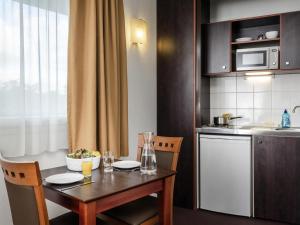 a kitchen with a table and chairs and a kitchen with a table and a kitchen at Aparthotel Adagio Access Paris Porte De Charenton in Charenton-le-Pont