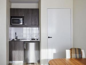 a kitchen with a sink and a microwave at Aparthotel Adagio Access Bordeaux Rodesse in Bordeaux