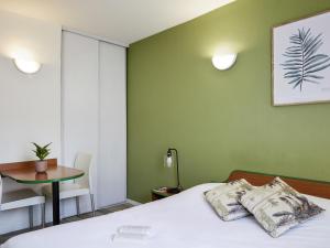 a bedroom with a bed and a table and a chair at Aparthotel Adagio Access Bordeaux Rodesse in Bordeaux