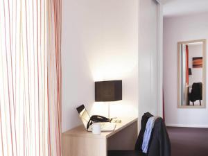 a room with a desk with a laptop and a lamp at Aparthotel Adagio Access Saint Louis Bâle in Saint-Louis +40 photos