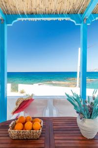 a basket of oranges sitting on a table near the ocean at Esperanza Home Mandrakia in Mandrakia