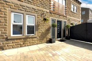 a brick house with a black gate and a building at RA7C Stylish Loft Stay in Batley