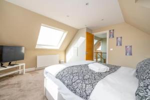 a bedroom with a large bed and a flat screen tv at RA7C Stylish Loft Stay in Batley