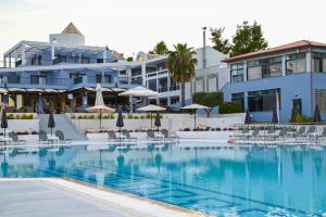 a pool with chairs and umbrellas in front of a hotel at Atrium Hotel in Pefkochori