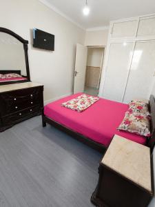 a bedroom with a pink bed and a mirror at F3 SALAMANDRE à CORNICHE CASA MAZA in Mostaganem