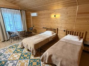 a room with two beds and a table and chairs at Kolsay Eco House in Saty