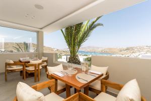 a restaurant with tables and chairs and a palm tree at Kallos of Mykonos in Ornos