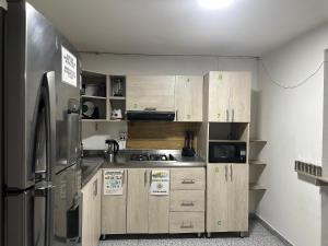 a kitchen with wooden cabinets and a stainless steel refrigerator at Habita Coliving La Palma in Medellín