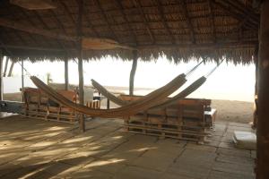 a hammock in a straw hut on the beach at Mojo Surf House in Popoyo