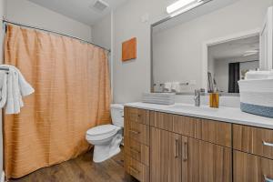 a bathroom with a sink and a toilet and a mirror at Spacious 2BR N Gulch Walk to Broadway & Rooftops in Nashville +41 photos