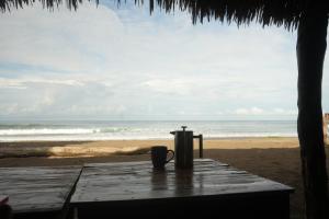 a table on the beach with a drink and a thermos at Mojo Surf House in Popoyo