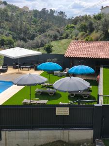 a group of umbrellas and tables and a pool at Casa Resineiro com Piscina, Garagem e Terraço in Proença-a-Nova