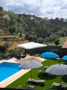 a view of a pool with umbrellas and chairs at Casa Resineiro com Piscina, Garagem e Terraço in Proença-a-Nova +52 photos