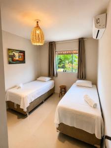 a bedroom with two beds and a chandelier at Condomínio Harmonia in Pipa +44 photos