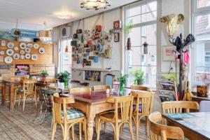 a restaurant with wooden tables and chairs and windows at Be my Guest House in Wijk aan Zee