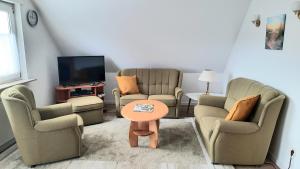 a living room with chairs and a table and a tv at Ferienwohnung Bandow in Woltersdorf