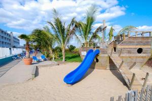 a playground with a blue slide in the sand at Carousel 1904 in Ocean City