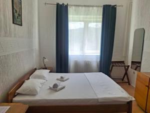 a bedroom with a bed with blue curtains and a window at Motel Buče in Berane