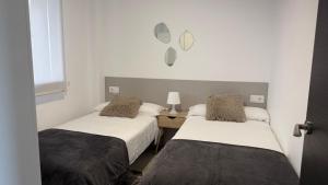 two beds in a room with white walls at Canelas 22 in Sanxenxo