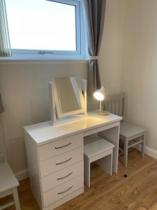 a white desk with a mirror and a lamp on it at Minch View Cabin 2, 1 Earlish in Earlish