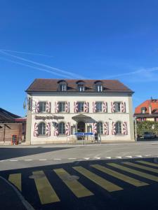 a large white building with red and white flags on it at Auberge de la Charrue in Romanel-sur-Lausanne