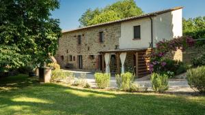 an old stone house with a garden in front of it at Agriturismo L'Accolta in Tuoro sul Trasimeno