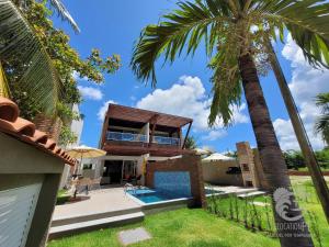 a house with a swimming pool and a palm tree at Vila Sol Serrambi in Porto De Galinhas