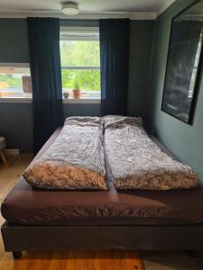 ein Bett in einem Schlafzimmer mit Fenster in der Unterkunft LeiraLy in Veblungsnes