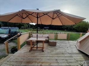 a table and an umbrella on a wooden deck at Glamping Bell Tent in Norton Saint Philip