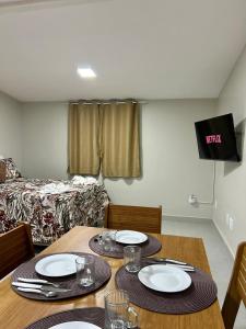 a dining room table with plates and glasses and a bed at Búzios Apartamento Charmoso in Búzios