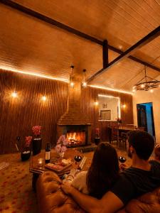 a group of people sitting on a couch in a living room with a fireplace at Refugio nas Alturas LANDIN & CHARM in Santo Antônio do Pinhal