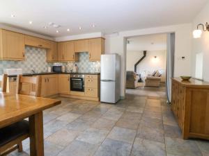 a kitchen with wooden cabinets and a white refrigerator at No 2 The Stables in Llangefni