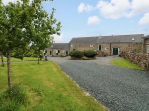 a large stone building with a tree and a gravel driveway at No 2 The Stables in Llangefni