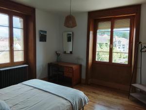 a bedroom with a bed and a dresser and windows at VILLA Douce Loue in Ornans