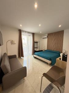 a bedroom with a bed and a couch and a chair at La dimora del duomo boutique suites & rooms in Terrasini