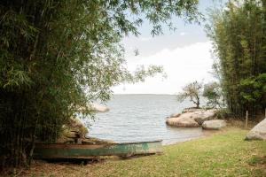 a body of water with a boat on the shore at Pousada Quinta do Cangueri in Imaruí