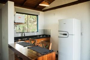 a kitchen with a refrigerator and a wooden table at Pousada Quinta do Cangueri in Imaruí