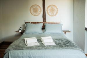 a bed with two white towels sitting on it at Pousada Quinta do Cangueri in Imaruí