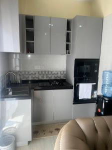 a kitchen with white cabinets and a sink and a microwave at Rosebank Villas in Luanda