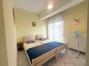 a bedroom with a bed and a window with a fan at An-Mary by vacapers in Iraklitsa