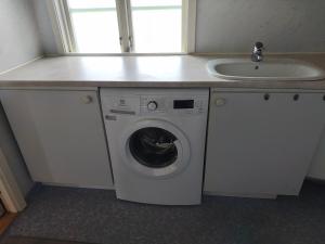 a washing machine under a counter next to a sink at The Red Butterfly 2 cottage in Månstad