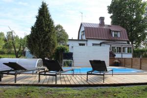 a deck with chairs and a table and a swimming pool at Villa Linnea in Hanko