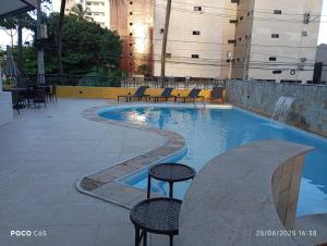 a swimming pool with chairs and a table in a building at Hotel Victory flat in Cabedelo