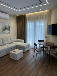 a living room with a white couch and a table at AMAD Aparthotel in Sarandë